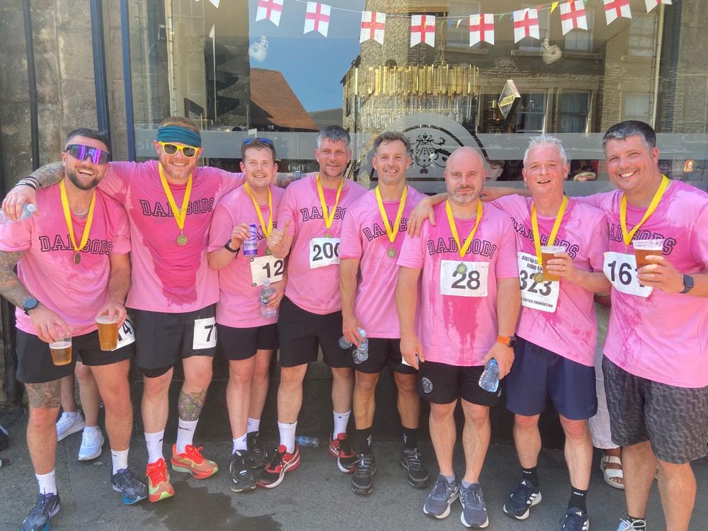 DadBods members in pink club shirts with medals and race numbers after a carnival fun run